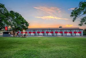 a large building with a grass field in front of it at Ramada by Wyndham Kingston in Kingston