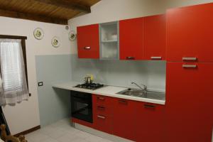 una cucina con armadi rossi e lavandino di Camping Ali Baba a Ceriale Altre 14 foto