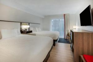 a hotel room with two beds and a flat screen tv at Ramada by Wyndham Kingston in Kingston +74 photos