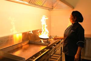 a woman in a kitchen with a cake on a stove at Cape Sigiriya in Sigiriya