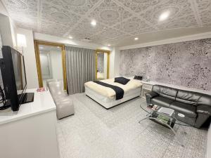 a bedroom with a bed and a tv and a couch at Que キュー -レジャーホテル in Shizuoka