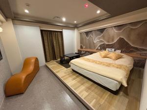 a bedroom with a large bed and a chair at Que キュー -レジャーホテル in Shizuoka