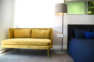 a yellow couch in a room with a bed and a lamp at Hollywood Guesthouse in Los Angeles