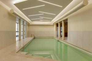 ein Hallenbad mit grünem Wasser in einem Gebäude in der Unterkunft HC Hotel Cremona Pilgrim's in Cicognolo