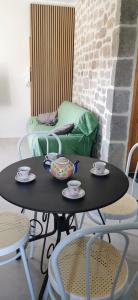 a black table with two chairs and cups and saucers at La ferme du lac Saint Front in Saint-Front