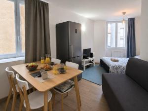a living room with a table and a room with a bed at Le Petit Forez, Cosy et Authentique in Saint-Bonnet-le-Château