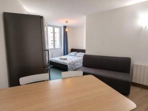 a living room with a couch and a bed at Le Petit Forez, Cosy et Authentique in Saint-Bonnet-le-Château