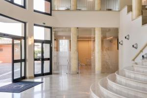 Die Lobby eines Gebäudes mit Treppe und Glastüren in der Unterkunft HC Hotel Cremona Pilgrim's in Cicognolo