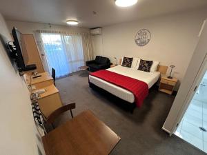 a bedroom with a bed and a couch and a table at ASURE Centrepoint Motel in Christchurch