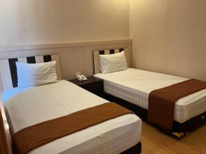 a hotel room with two beds and a phone at Grand Duta Hotel in Palu