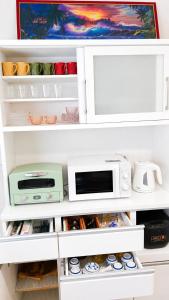 a kitchen pantry with white cabinets and a microwave at オリーブママのヤド 凪 バーベキュー機材レンタル可 in Shodoshima +14 photos