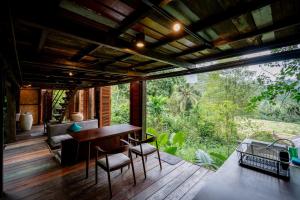 a room with a table and chairs on a deck at Kalpa House Sidemen in Sidemen +15 photos