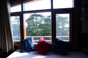 a bed with three pillows in front of a window at Hotel King Palace in Shimla