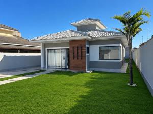 a house with a green lawn in front of it at Beach Loft - Design e Estilo in Maricá
