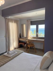 a bedroom with a bed and a desk and a window at AMORÉA Jacuzzi Suites Evia in Eretria