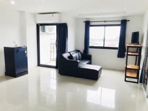 a living room with a black chair and a refrigerator at DM udon in Udon Thani