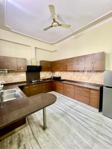 a large kitchen with wooden cabinets and a ceiling fan at ZenRoofs-3 BHK Bungalow in Jaipur