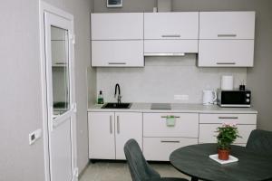 a kitchen with white cabinets and a table at Marsas 2 in Zarasai