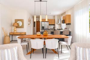 a kitchen and dining room with a wooden table and white chairs at PARATY Apartment l Complex Ocean Terraces in Poste Lafayette
