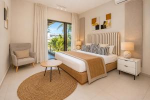 a bedroom with a bed and a chair and a window at PARATY Apartment l Complex Ocean Terraces in Poste Lafayette
