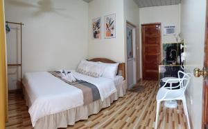 a bedroom with a bed and a white chair at Victoria's Inn in Siquijor