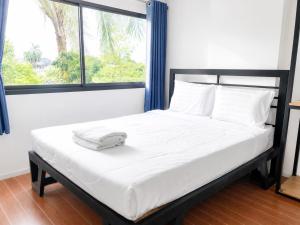 a bed with a white blanket on it with a window at DM udon in Udon Thani