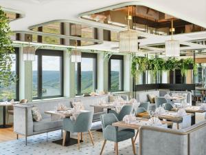 a restaurant with tables and chairs and windows at Jakobsberg Nature Resort - Hotel & Golf in Boppard