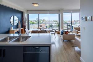 a kitchen with a sink and a living room at Zara Tower – Luxury Suites and Apartments in Sydney