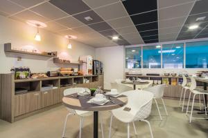 un ristorante con due tavoli e sedie e una cucina di Nemea Appart Hotel Quai Victor Tours Centre a Tours