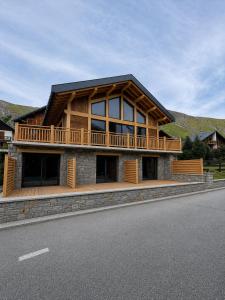 a large wooden house with a balcony on the side of the road at Chalet Jogidi in Saint-Sorlin-dʼArves