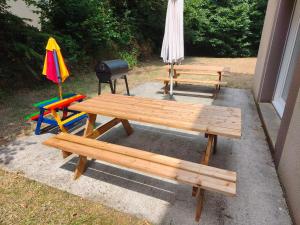 a picnic table and a grill with two benches and an umbrella at LES MAISONS SERENITY Plouzané in Plouzané