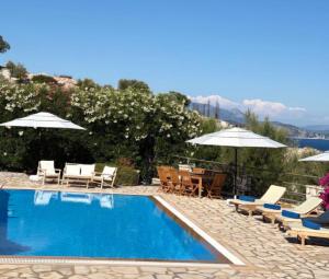 a swimming pool with chairs and umbrellas at Villa QuintaBella in Sivota