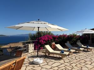 a group of chairs and an umbrella on a patio at Villa QuintaBella in Sivota +23 photos