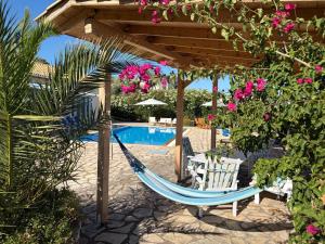 a hammock under a pergola next to a pool at Villa QuintaBella in Sivota