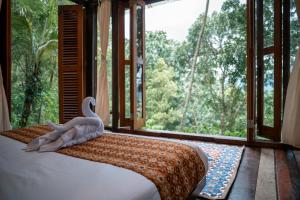 a swan sitting on a bed in a room with a window at Folky House Sidemen in Silebeng