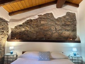 a bedroom with a stone wall and a bed at Osini Ecciu Home in Osini