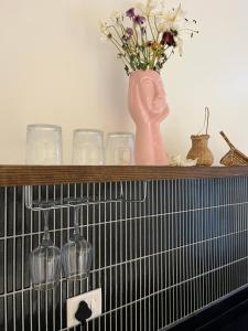 a shelf with glasses and a vase with flowers on it at Noi Homes - Entire 2BHK Luxury Flat with Parking, Kitchen and Balcony in Jorhat