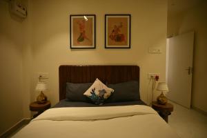 a bedroom with a bed with three pictures on the wall at Noi Homes - Entire 2BHK Luxury Flat with Parking, Kitchen and Balcony in Jorhat