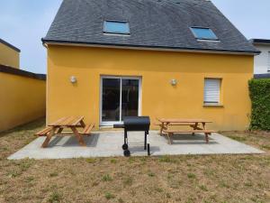 a yellow building with two picnic tables and a grill at MAISON SERENITY Bohars in Bohars
