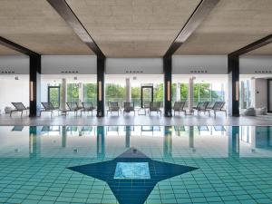 a swimming pool with chairs and tables in a building at Jakobsberg Nature Resort - Hotel & Golf in Boppard