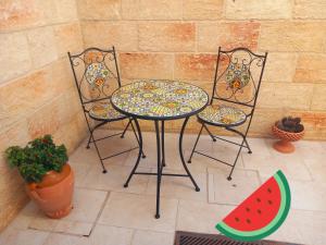 a table and two chairs with a table and a slice of watermelon at Casa Vacanze 9 Cavalieri in Maglie