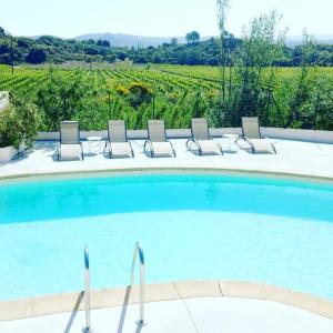 a swimming pool with chairs and a view of a vineyard at Les chalets du Relais d'Aguilar in Tuchan