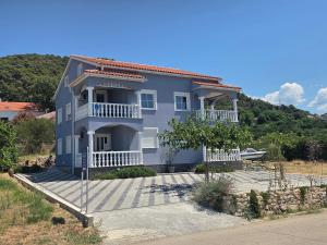 a blue house with a balcony and a yard at Apartmani Meglić in Barbat na Rabu