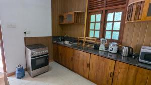 a kitchen with wooden cabinets and a stove at Margarita Leisure in Wadduwa