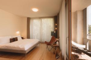 a bedroom with a bed and a chair and a window at Casa Caminada in Fürstenaubruck
