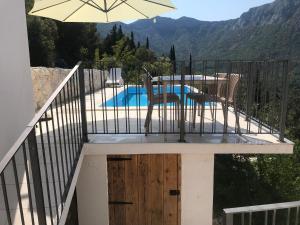 a balcony with a table and an umbrella next to a pool at HOLIDAY HOME m&n in Zaostrog +5 photos