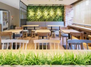 a restaurant with tables and chairs and a green wall at Super Hotel Kushiro Kurogane in Kushiro