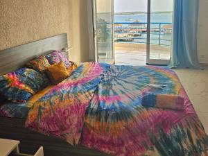 a bedroom with a colorful bed with a view of the ocean at Hotel Cap du Sine Saloum in Ndangane