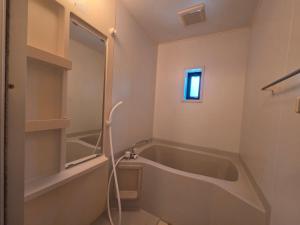 a bathroom with a bath tub and a window at アパートメントホテル憩 in Yanagawa
