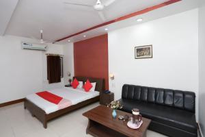 a bedroom with a bed and a couch and a table at Hotel O Crown Hidden Residency in Satna